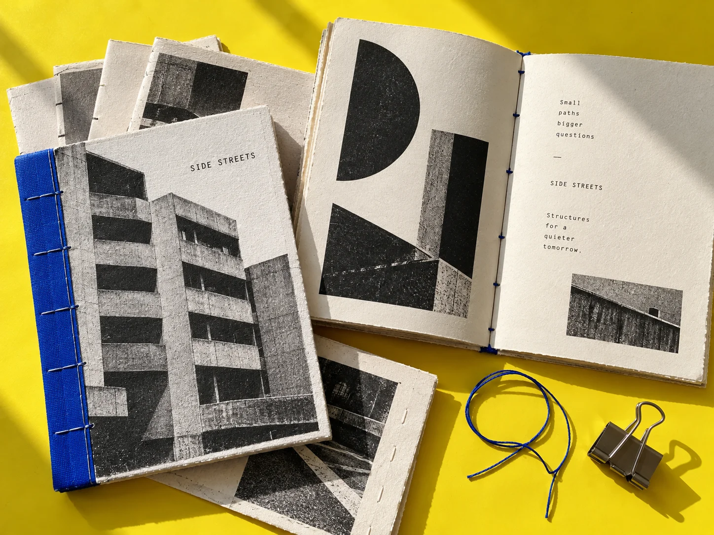 A stitched Side Streets artist book and folded signatures on a yellow worktable